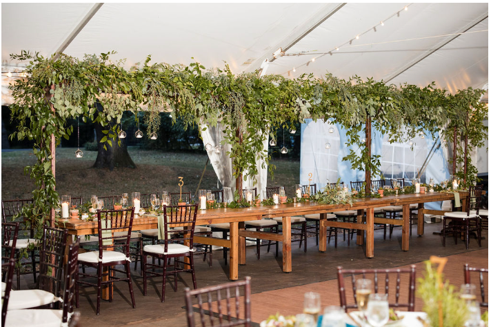 A long wooden table and chairs under a tent.