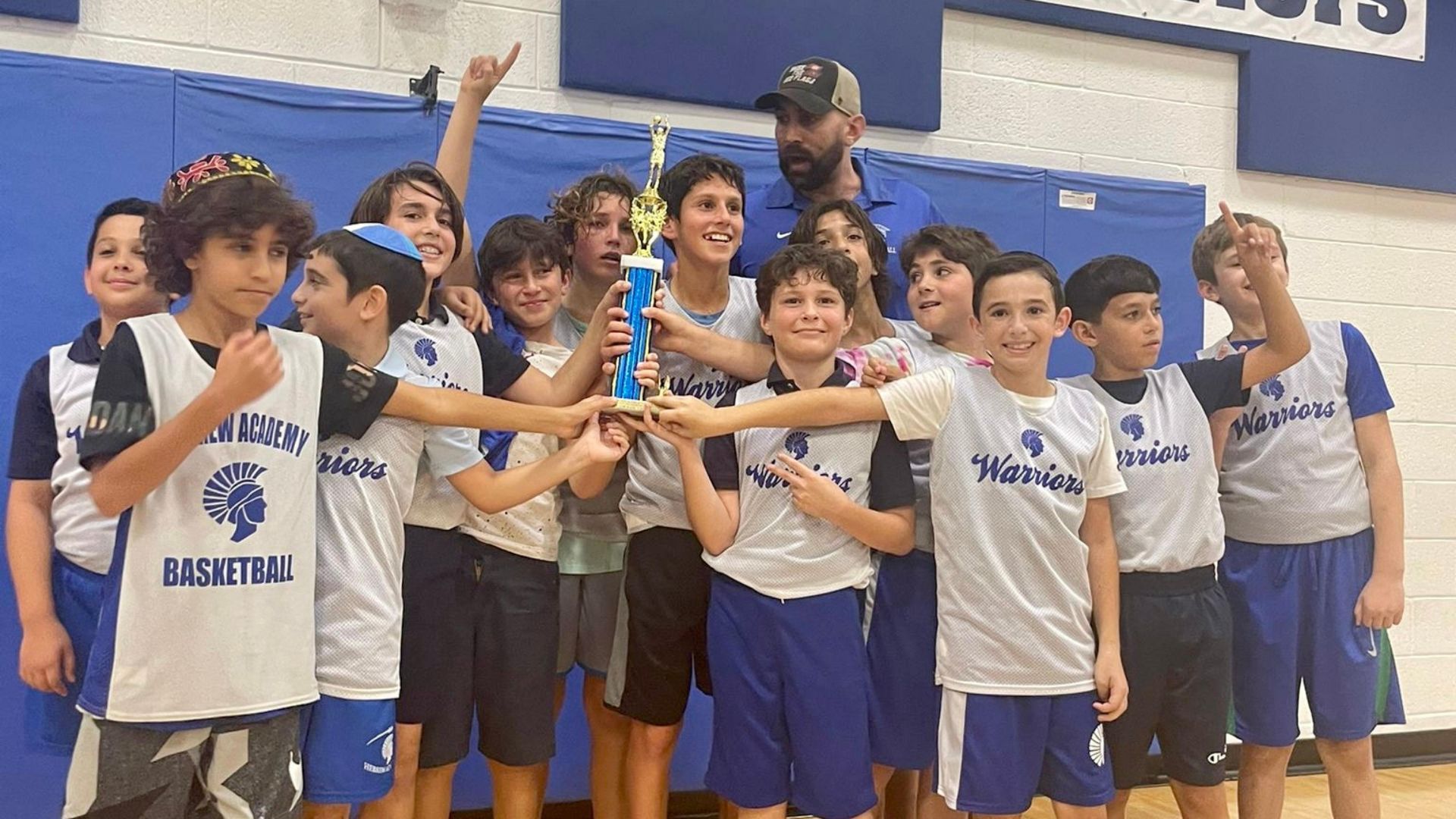 A group of young boys holding a trophy in a gym