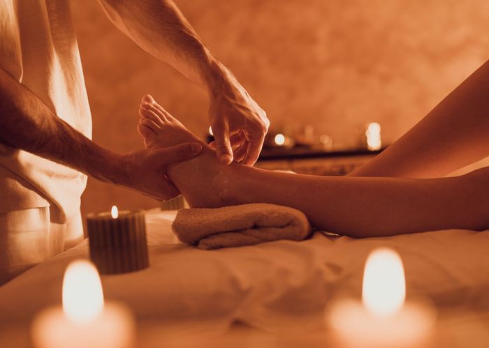 A Woman Is Laying On A Massage Table With Candles And Bowls — Melbourne, VIC — Cattleya Thai Massage & Waxing