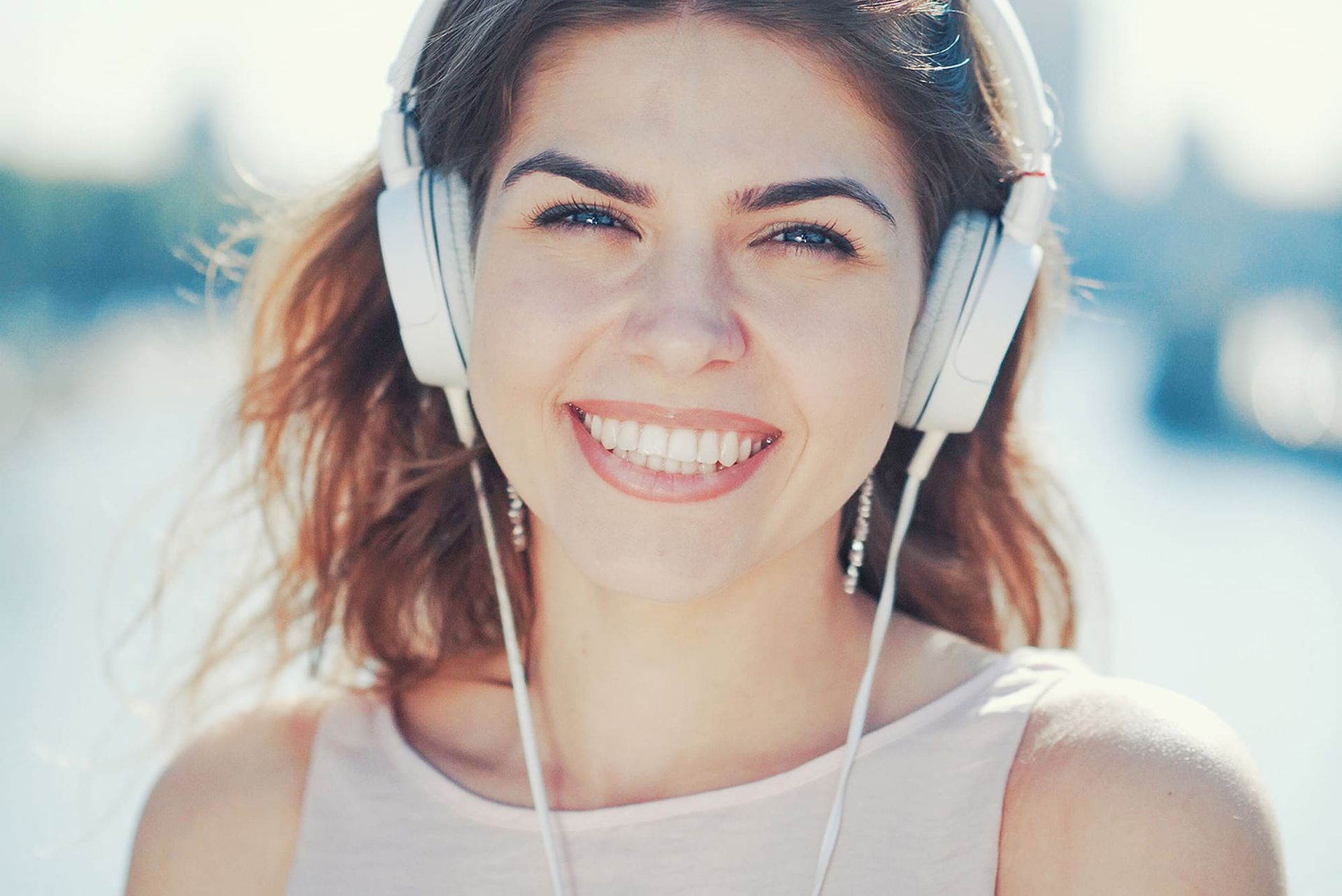 A woman wearing headphones is smiling and looking at the camera.