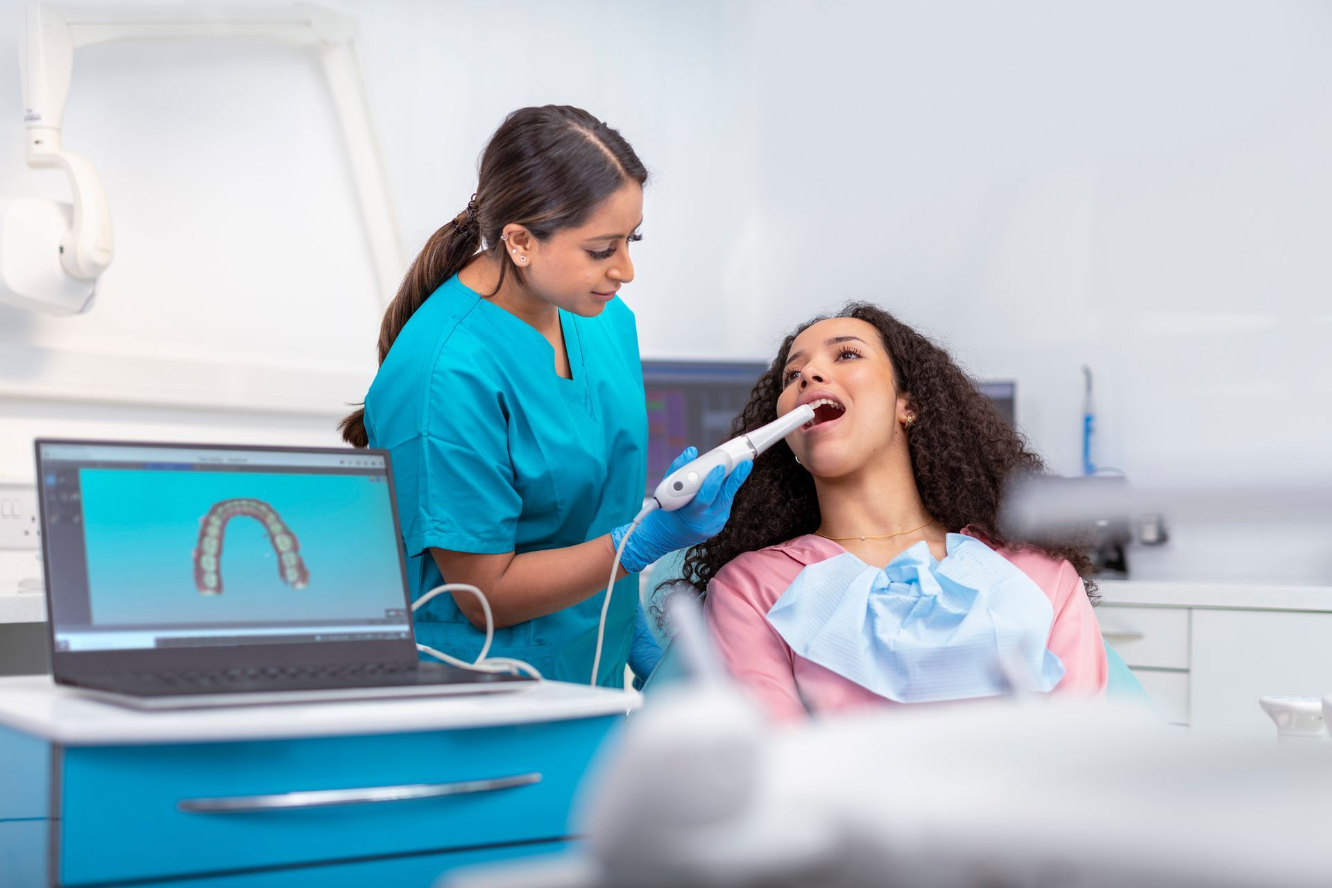 A dental care professional using a digital scanner to examine a patient's teeth in a modern clinic.