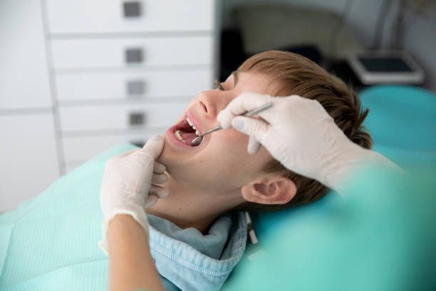 A young boy is getting his teeth examined by a dentist.