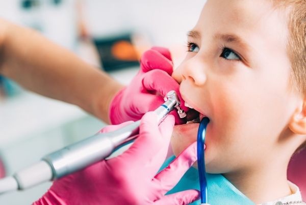 A young boy is getting his teeth examined by a dentist.