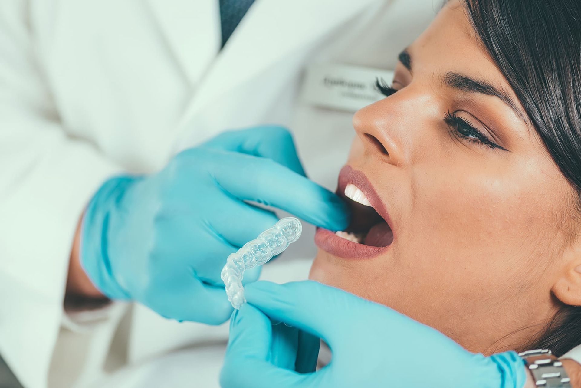 A woman is getting her teeth whitened by a dentist.