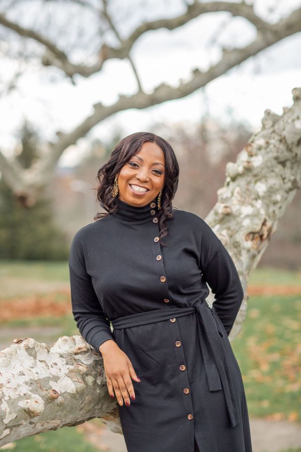 A man is holding a dog in his arms and the dog is wearing a sweater.