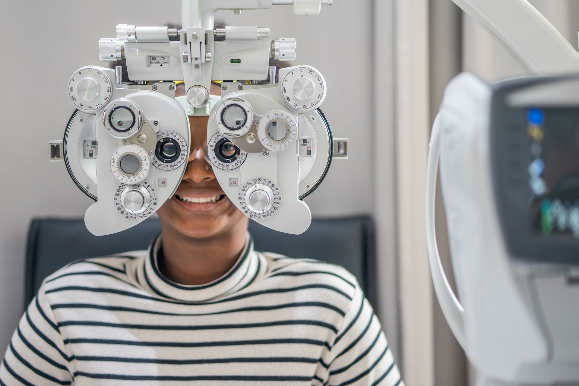 A teen girl goes through an eye test on a phoropter.