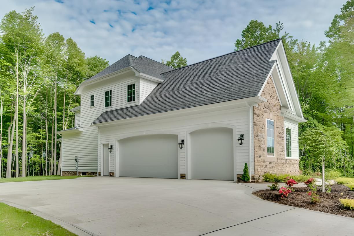 A white house with three garage doors and a driveway