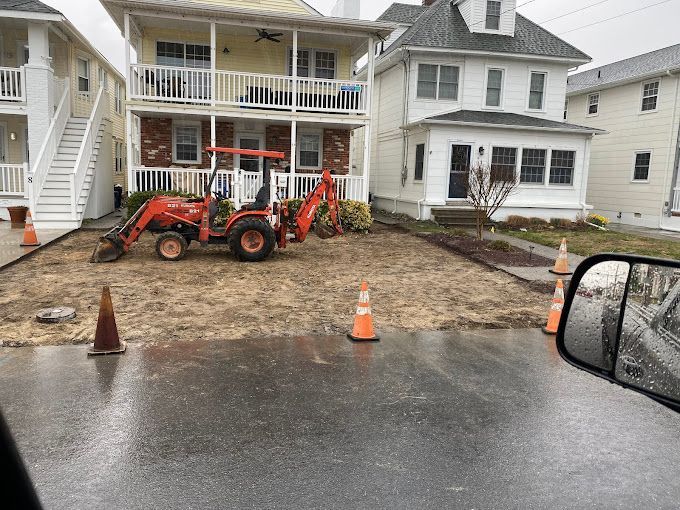 A red tractor is parked in front of a house with new asphalt parking area installed by stone works masonry inc.