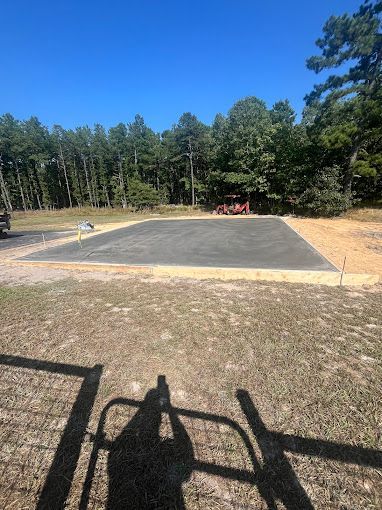 A shadow of a person is cast on the ground in front of a blacktopped surface built by stone works masonry inc.