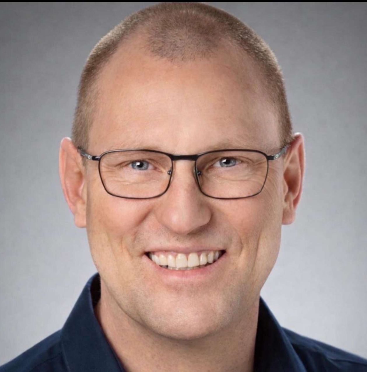 Deck overlooking blue water, gazebo, and trees under a clear sky. Black railing.