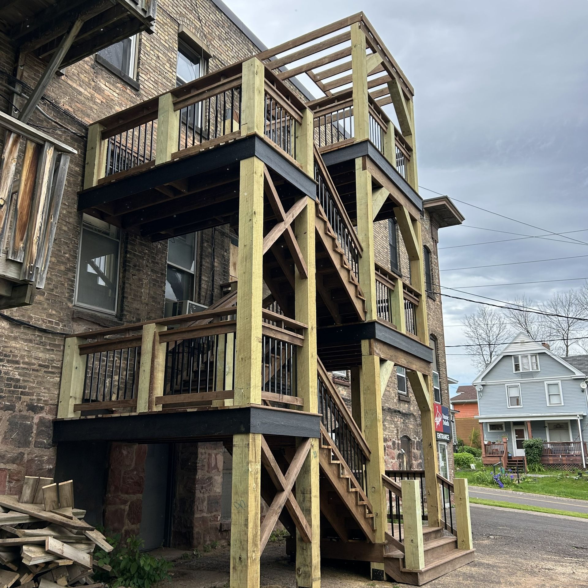 Multi-level wooden deck and staircase attached to a brick building.