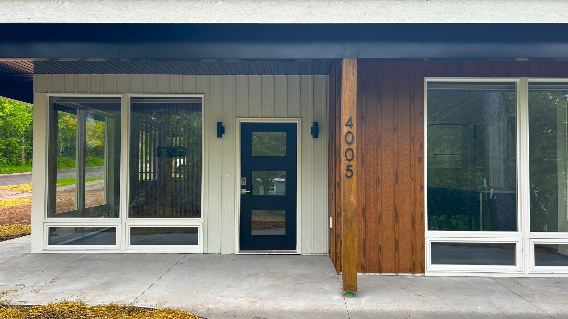 Modern home exterior with large windows, black door, and wooden accents.
