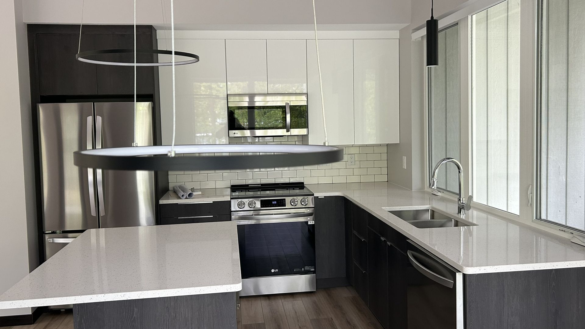 Modern kitchen with white and dark gray cabinets, stainless steel appliances, and a quartz countertop.