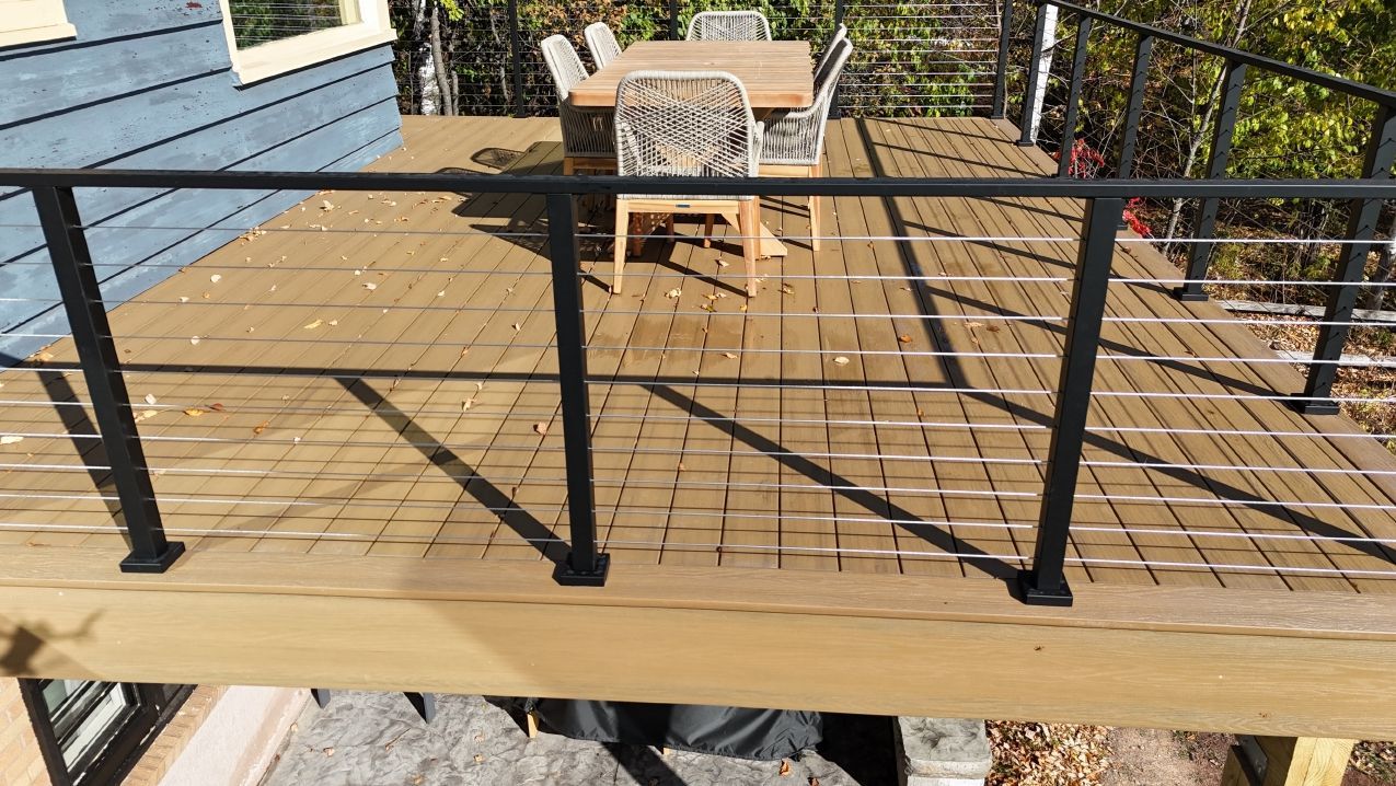 Wooden deck with black railings and outdoor dining set.