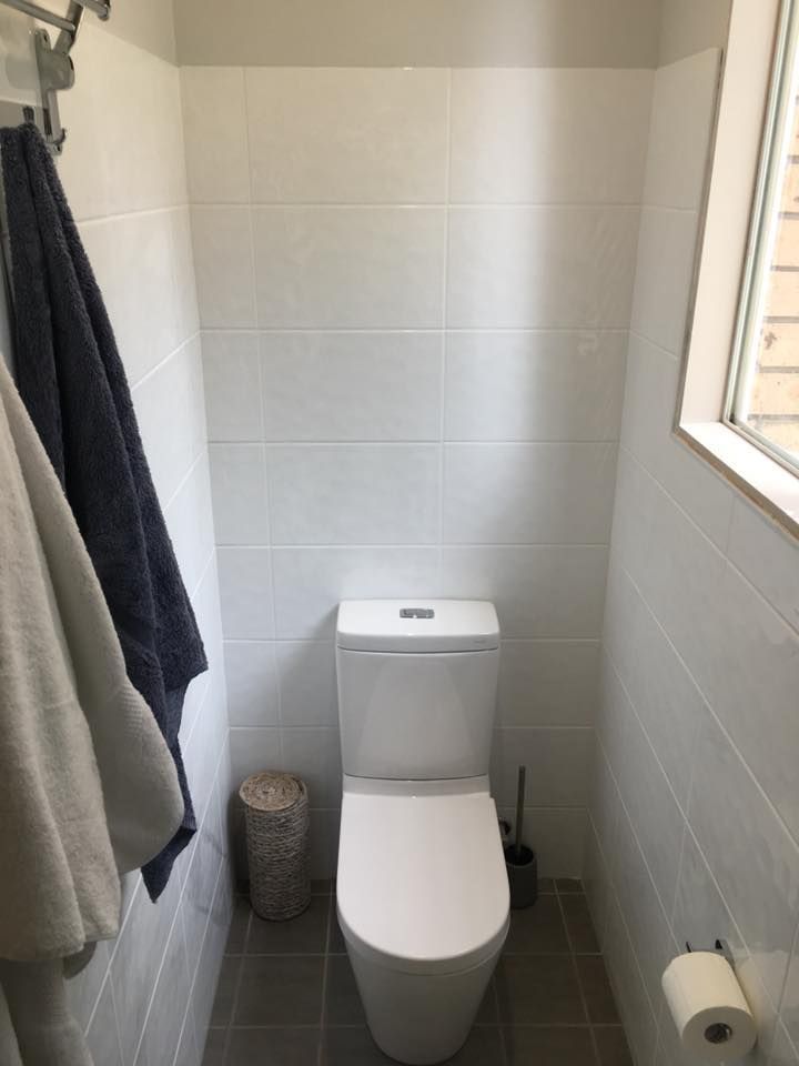 Small Bathroom With a White Toilet, Gray Tiles, and a Small Window — ABV Plumbing In Woy Woy, NSW
