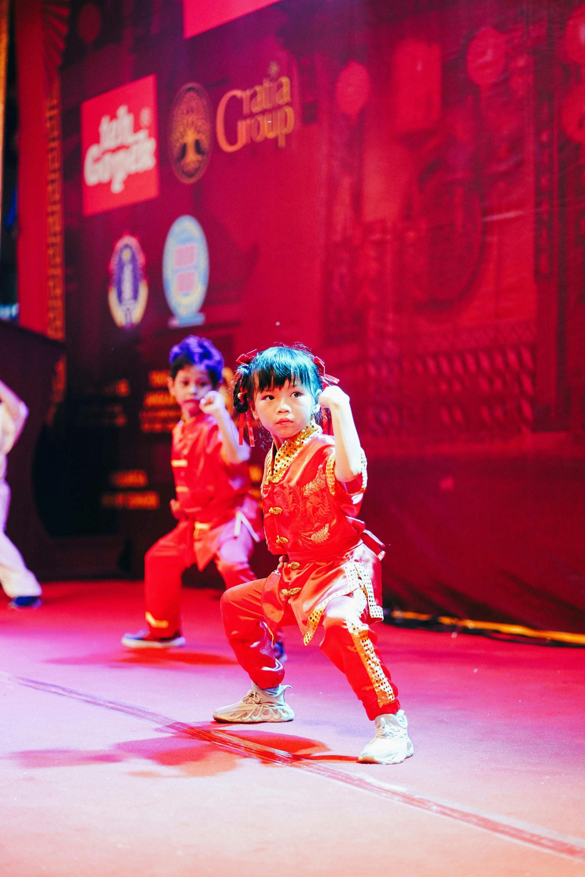 A group of children are performing on a stage in front of a sign that says ' gala group '