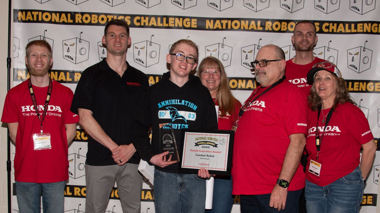 A group of girls are holding their robots in front of a crowd