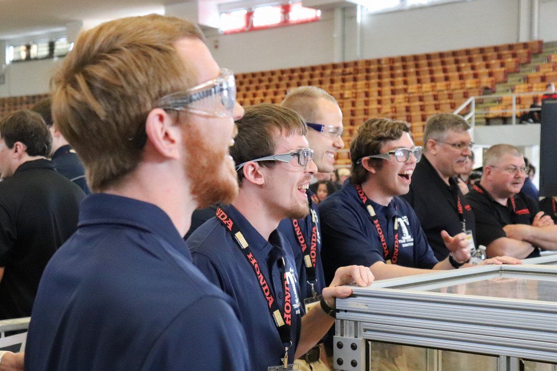 A group of men wearing glasses and a lanyard with the letter t on it