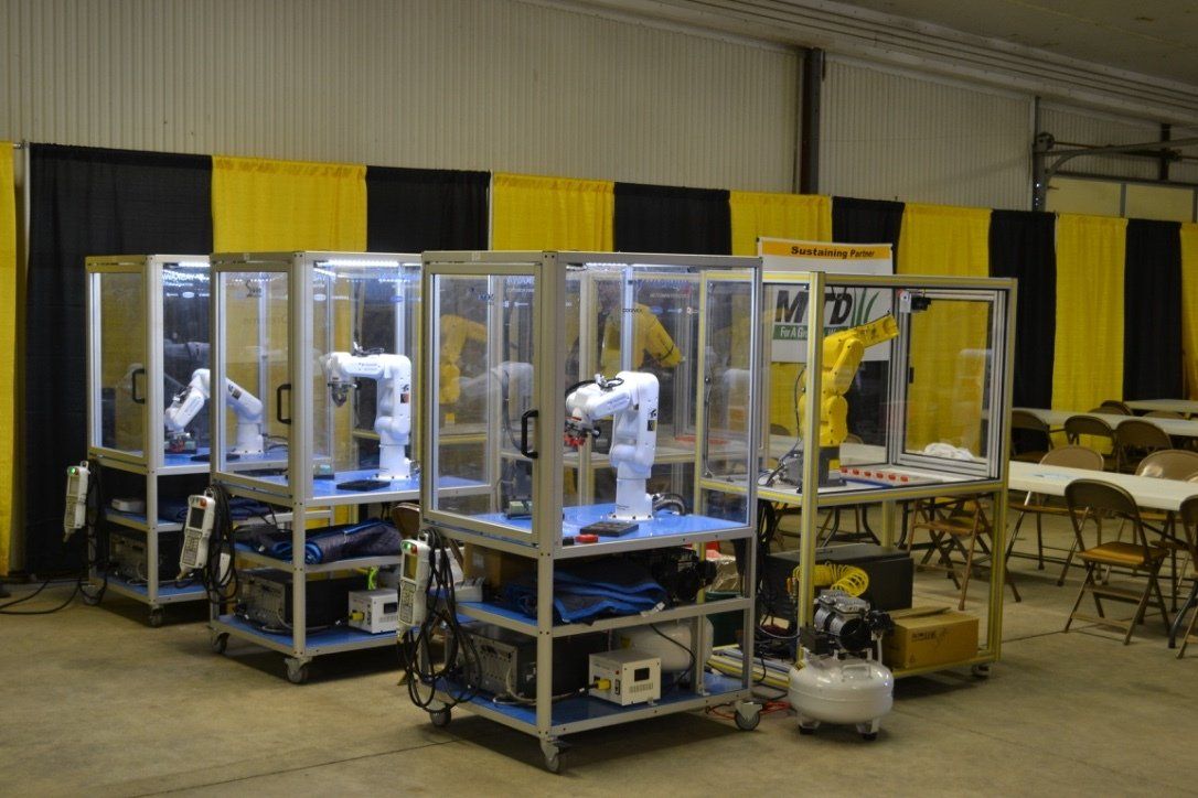 A row of robots are sitting in a room with tables and chairs.