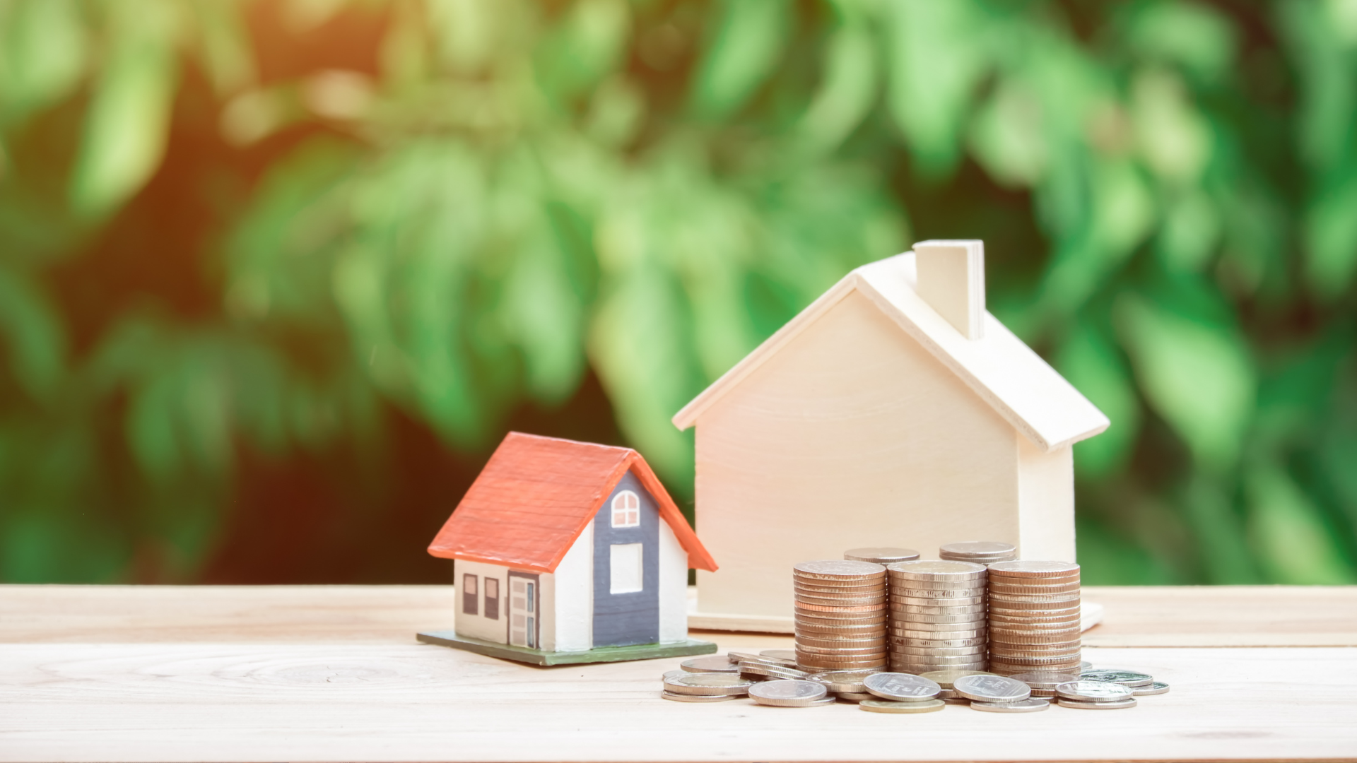 Two toy houses with coins stacked nearby, representing real estate investment.