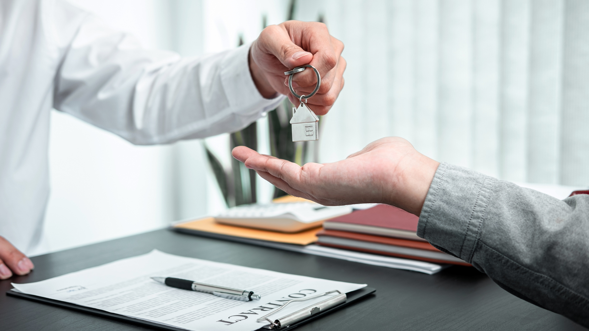 Person handing house keys to another person.