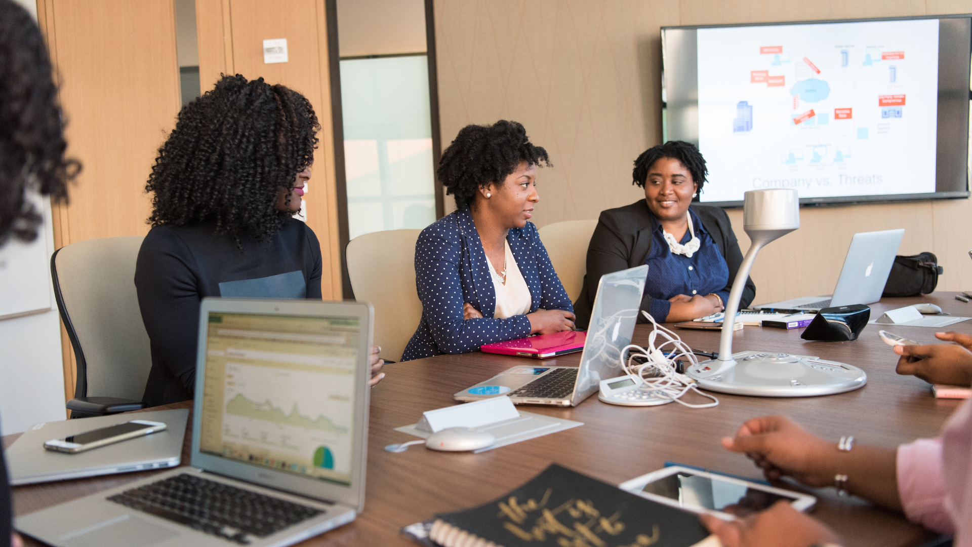 Group of Black women collaborating around a conference table with laptops.