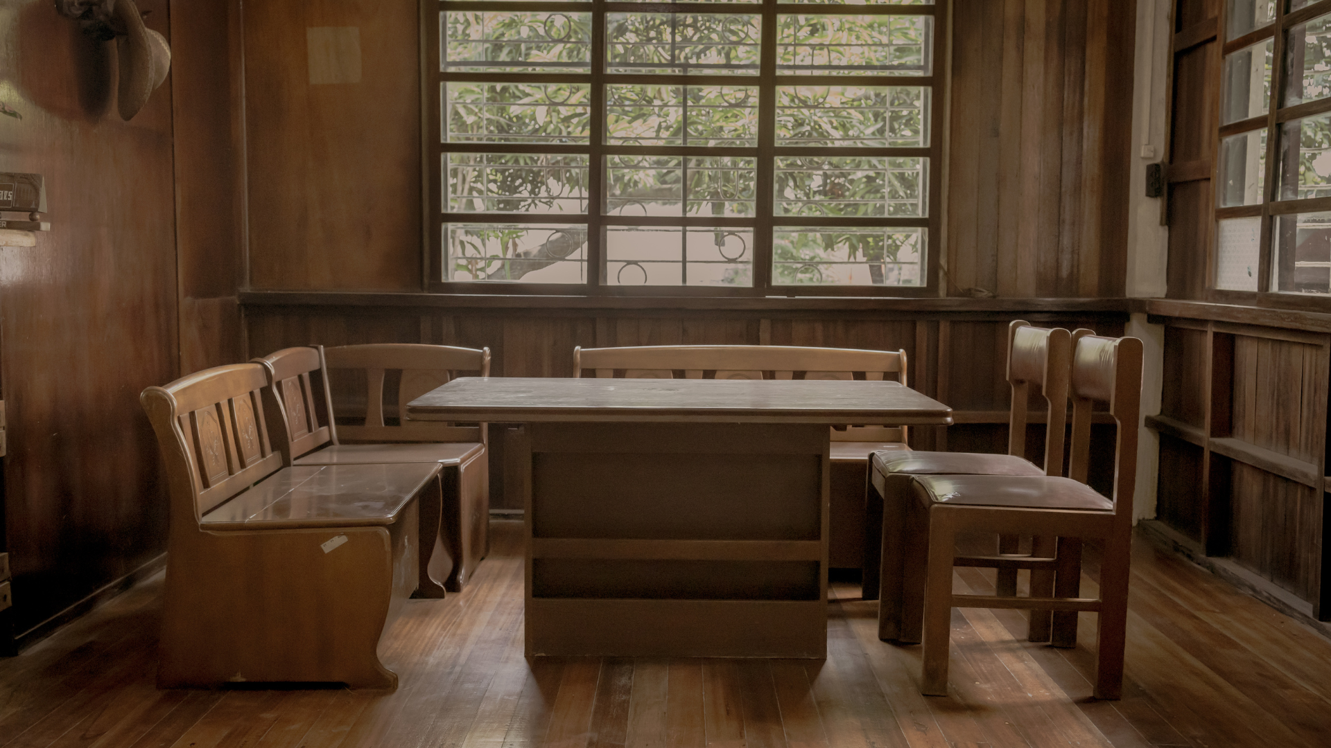 Wooden dining room with table, benches, and chairs near windows.