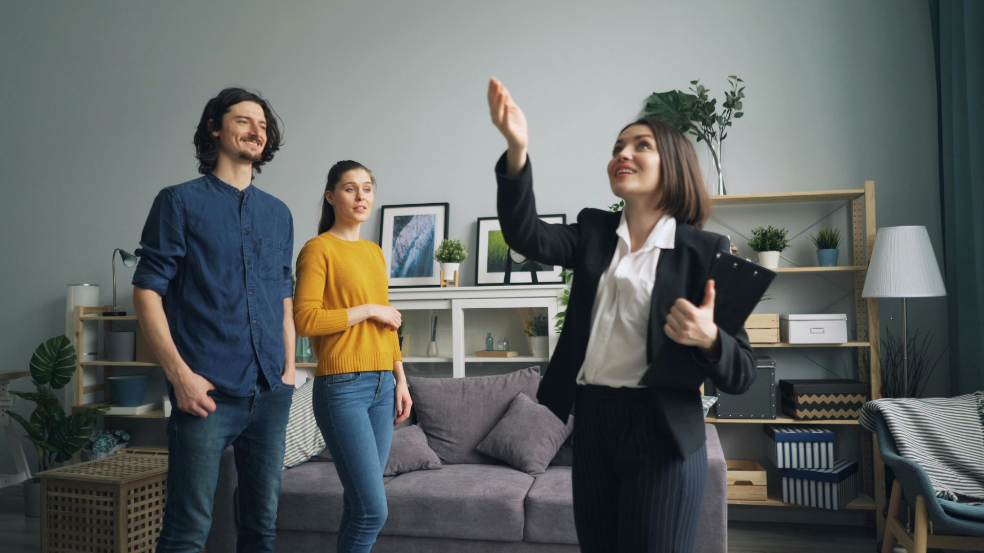 Real estate agent showing client a house model and paperwork at a desk.