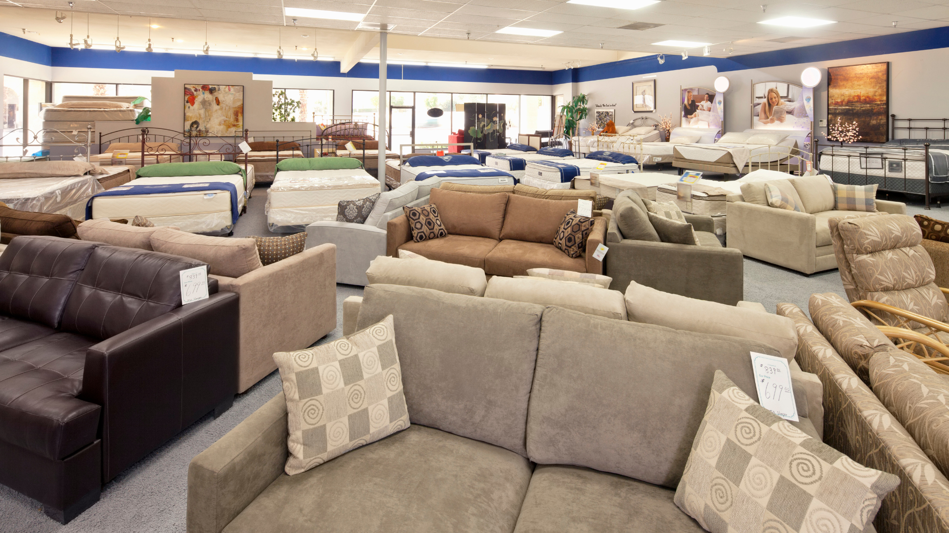 Furniture showroom with various sofas and mattresses on display.