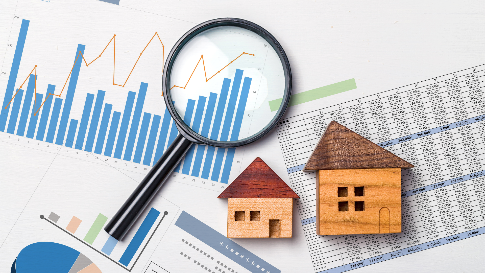 Magnifying glass over house models and real estate charts.