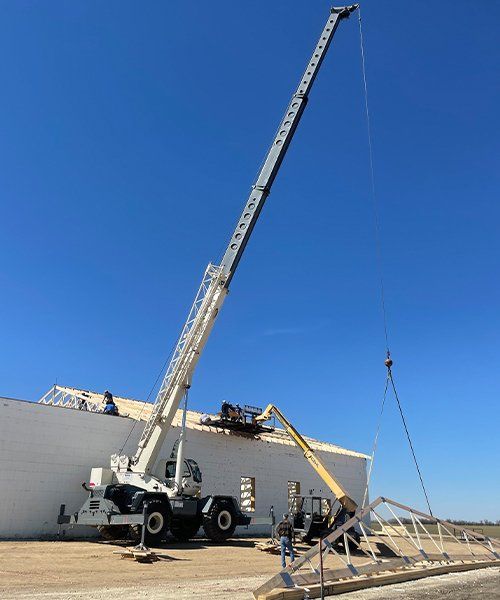 white crane on site installing truss on building
