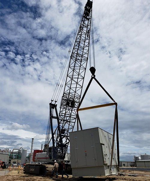 industrial crane lifting materials on job site with white clouds in background