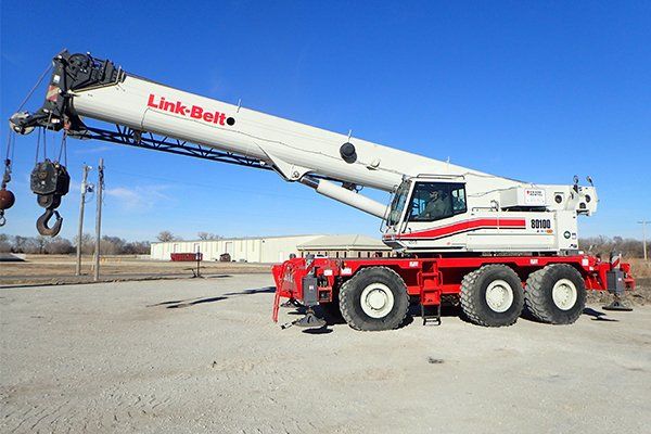 red and white link blet crane with large hooks in parking lot