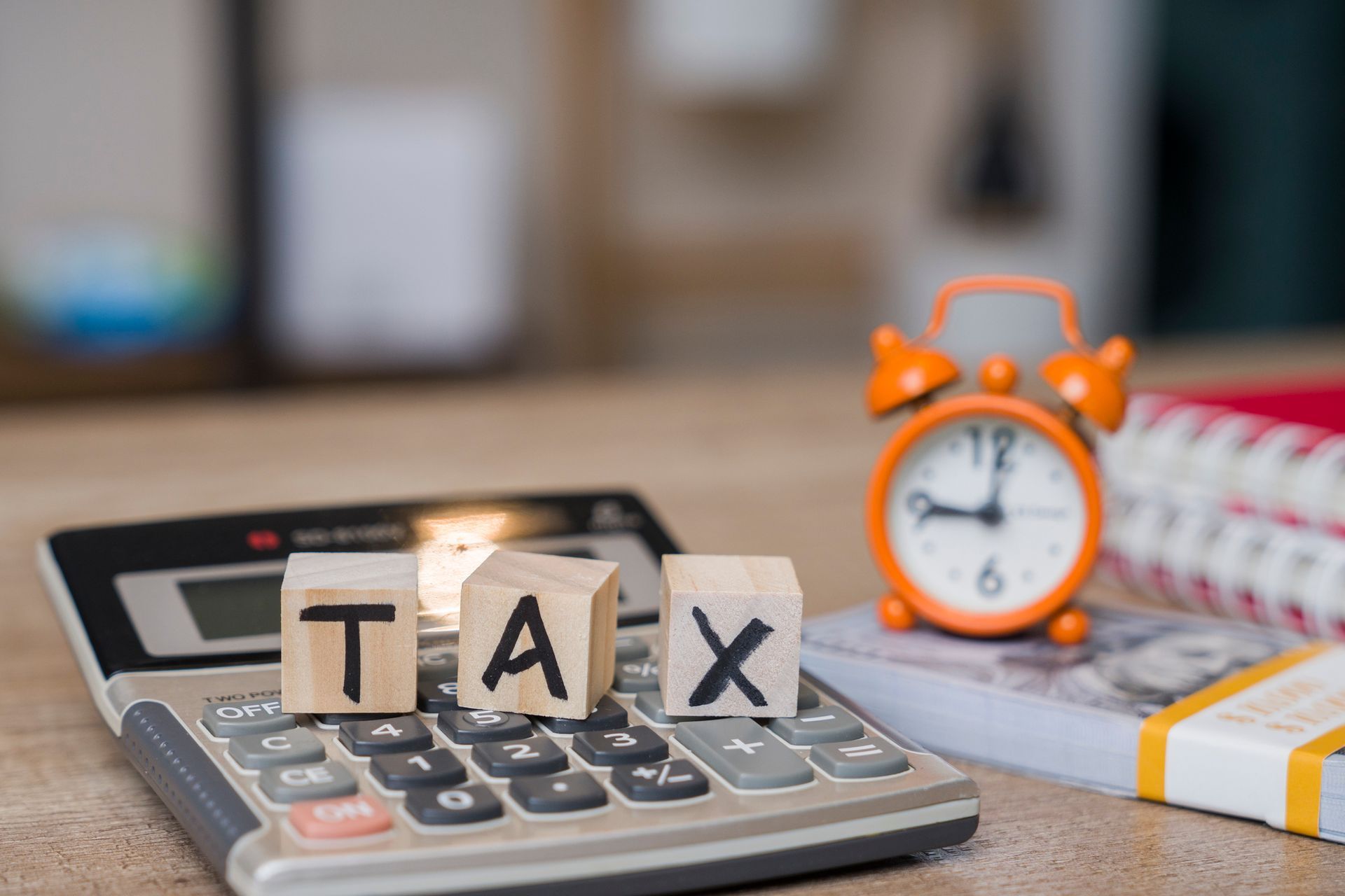 Calculator with TAX blocks and orange alarm clock.