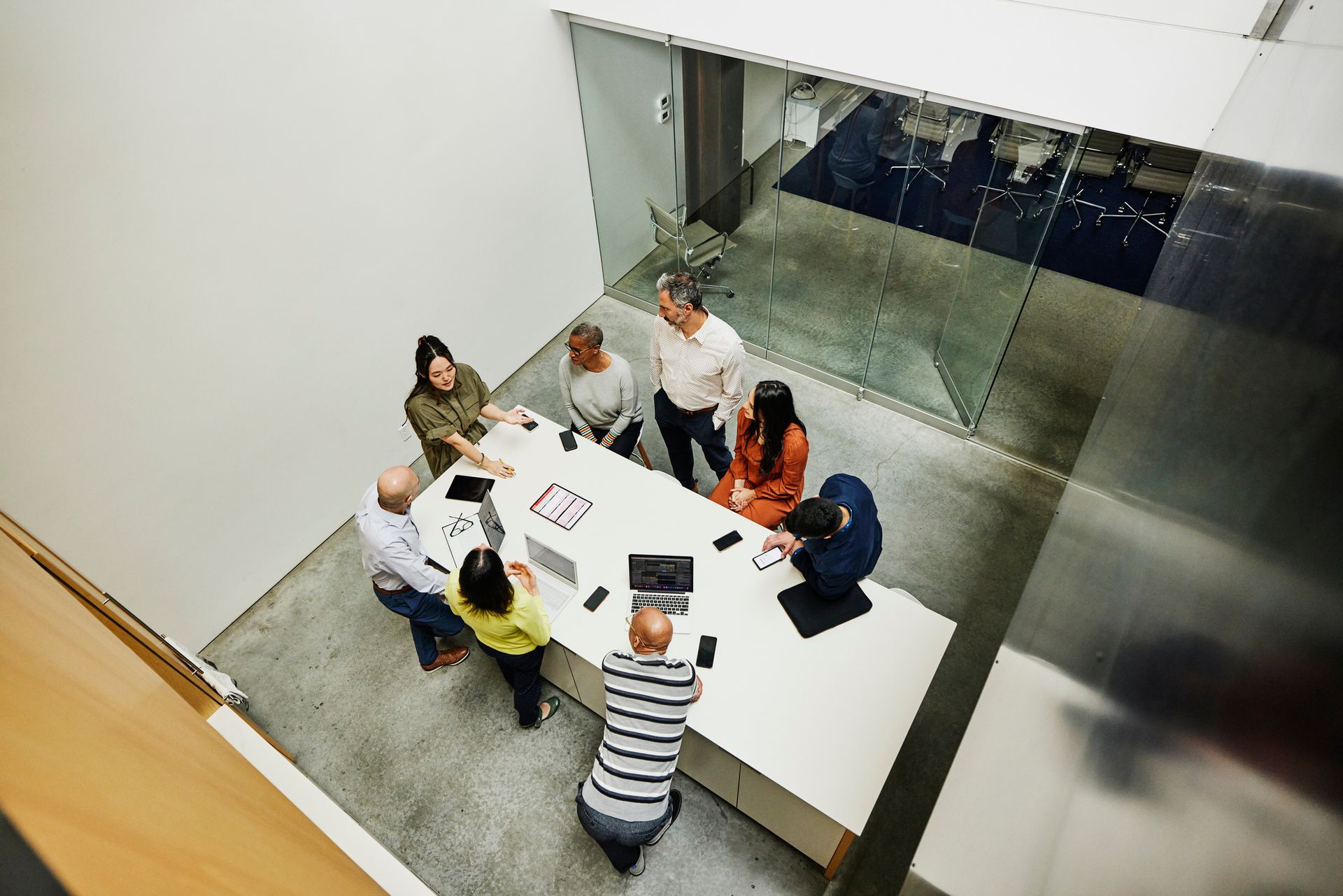 People in a meeting around a white table in a modern office setting.