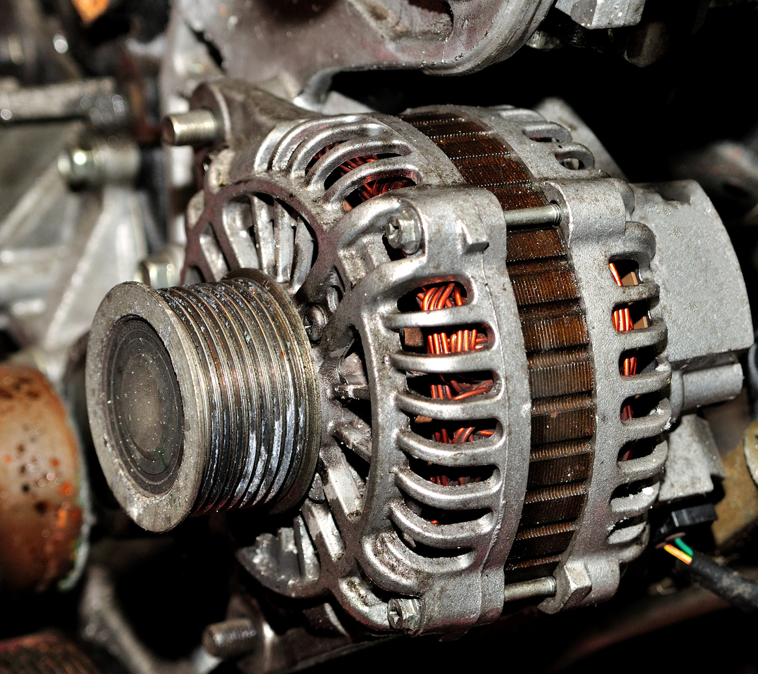 A close up of an alternator on a car engine