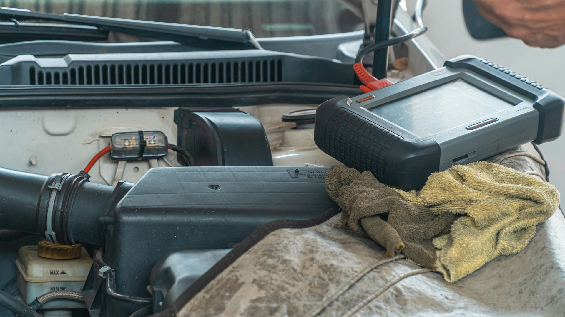 A person is working on a car engine with a tool.