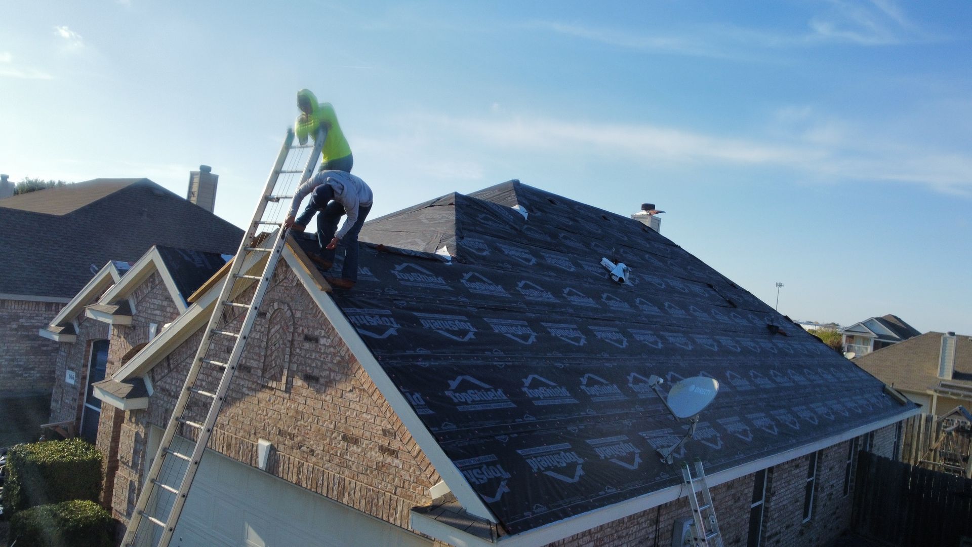 Two men are working on the roof of a house.