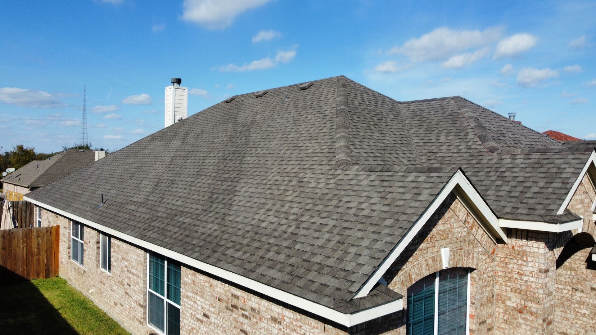 A brick house with a gray roof and a chimney.