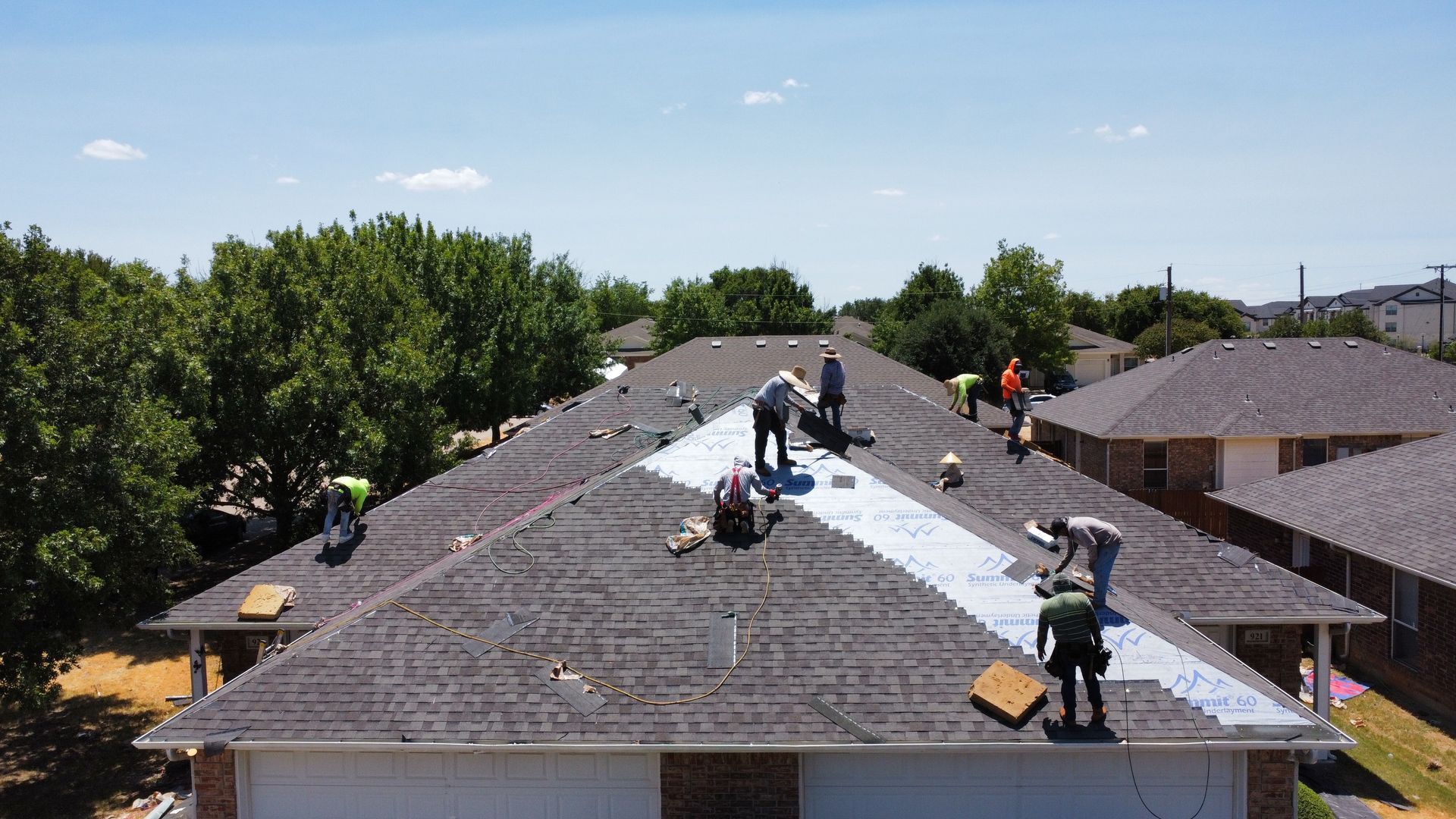 A group of people are working on the roof of a house.