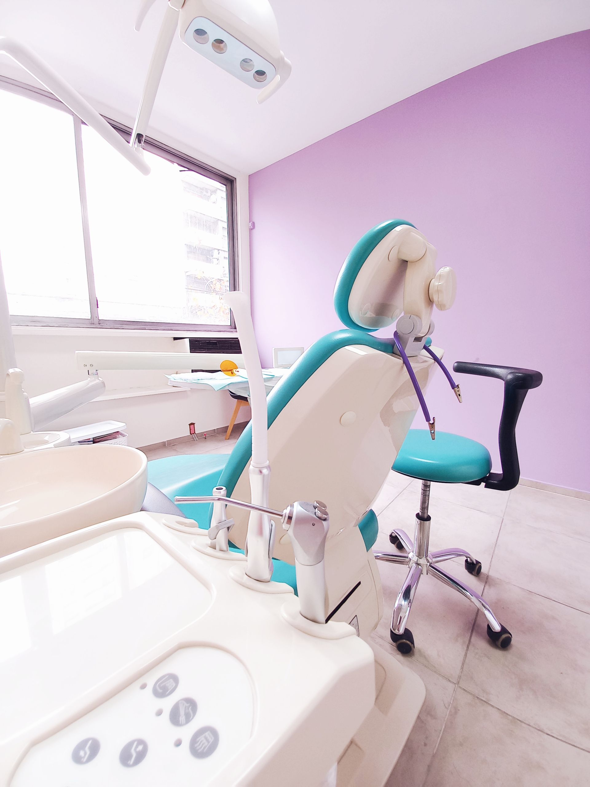 Una silla dental en una habitación con paredes moradas.