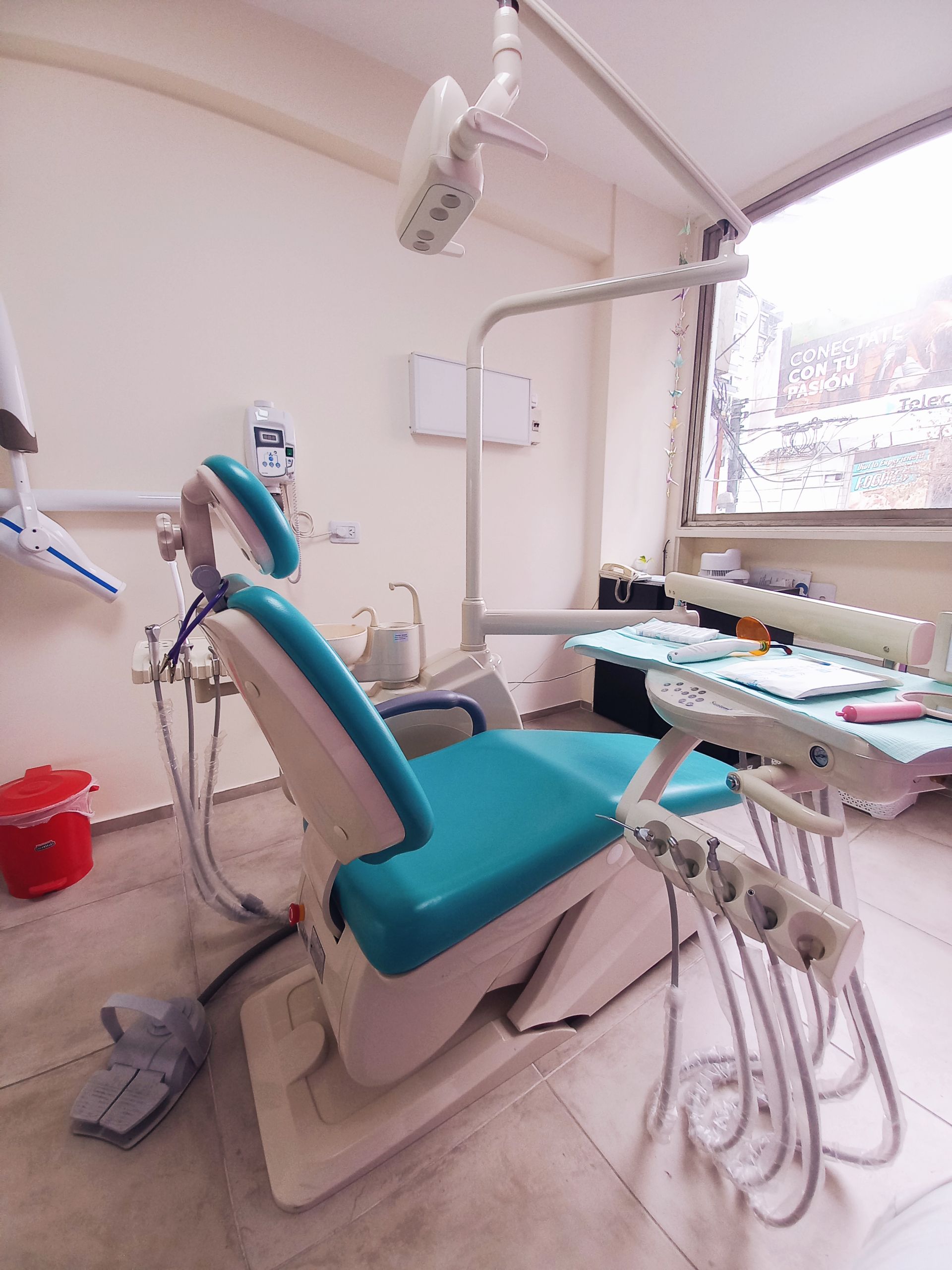 Un consultorio dental con una silla azul y una mesa.