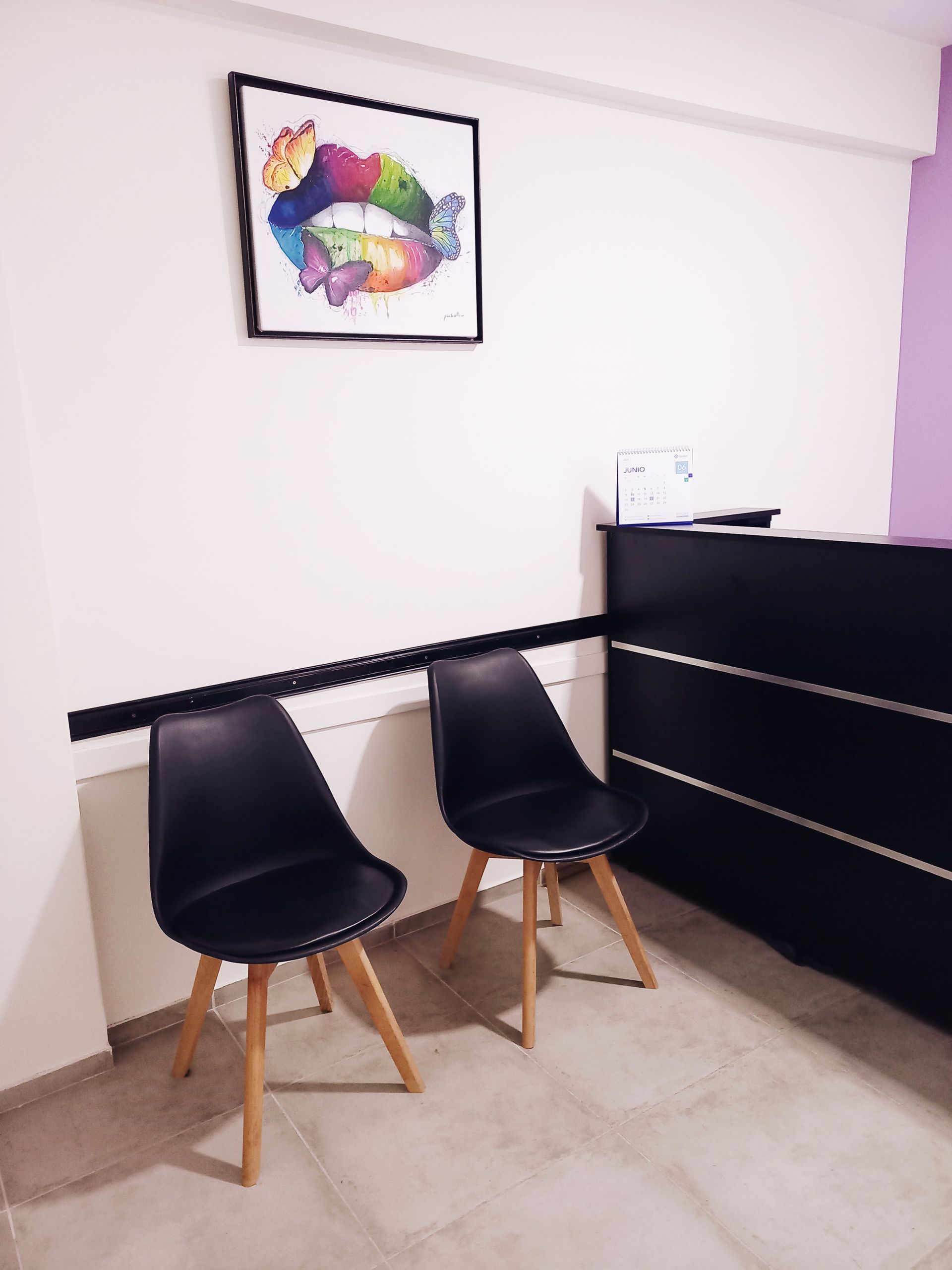 Una sala de espera con dos sillas y un cuadro en la pared.