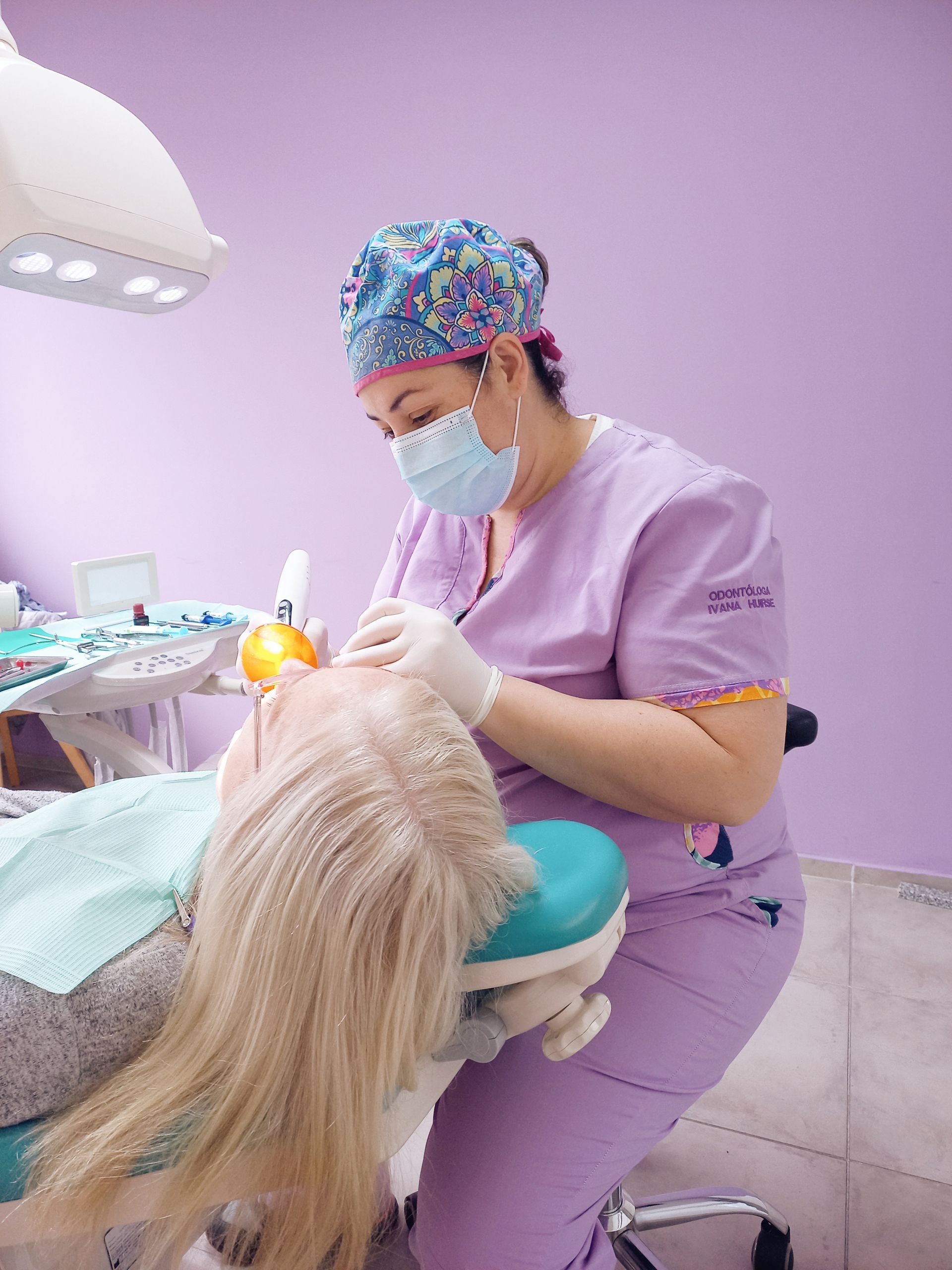 Una mujer está sentada en una silla dental mientras un dentista le examina los dientes.