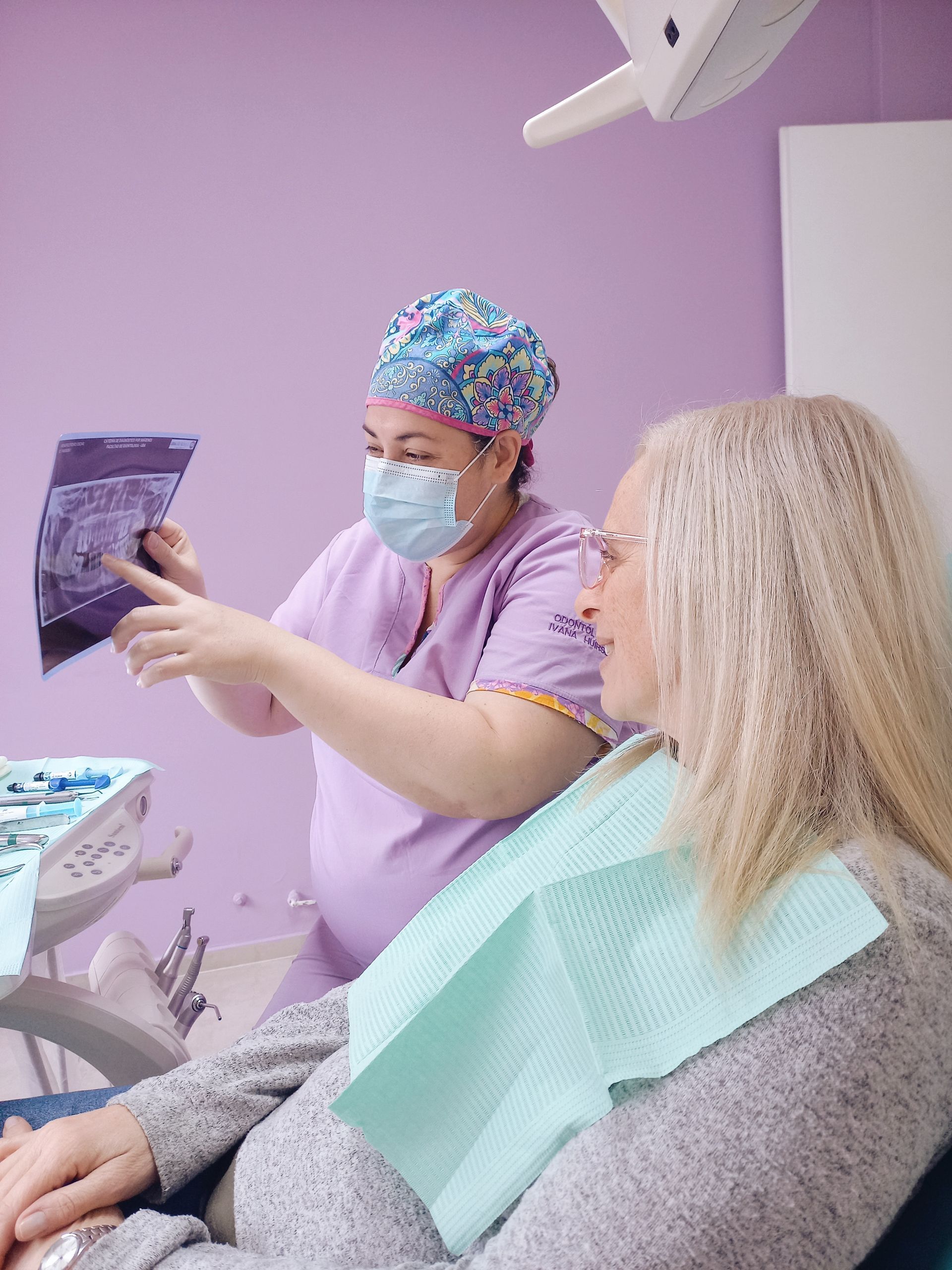 Una mujer está sentada en una silla dental mientras un dentista le examina los dientes.