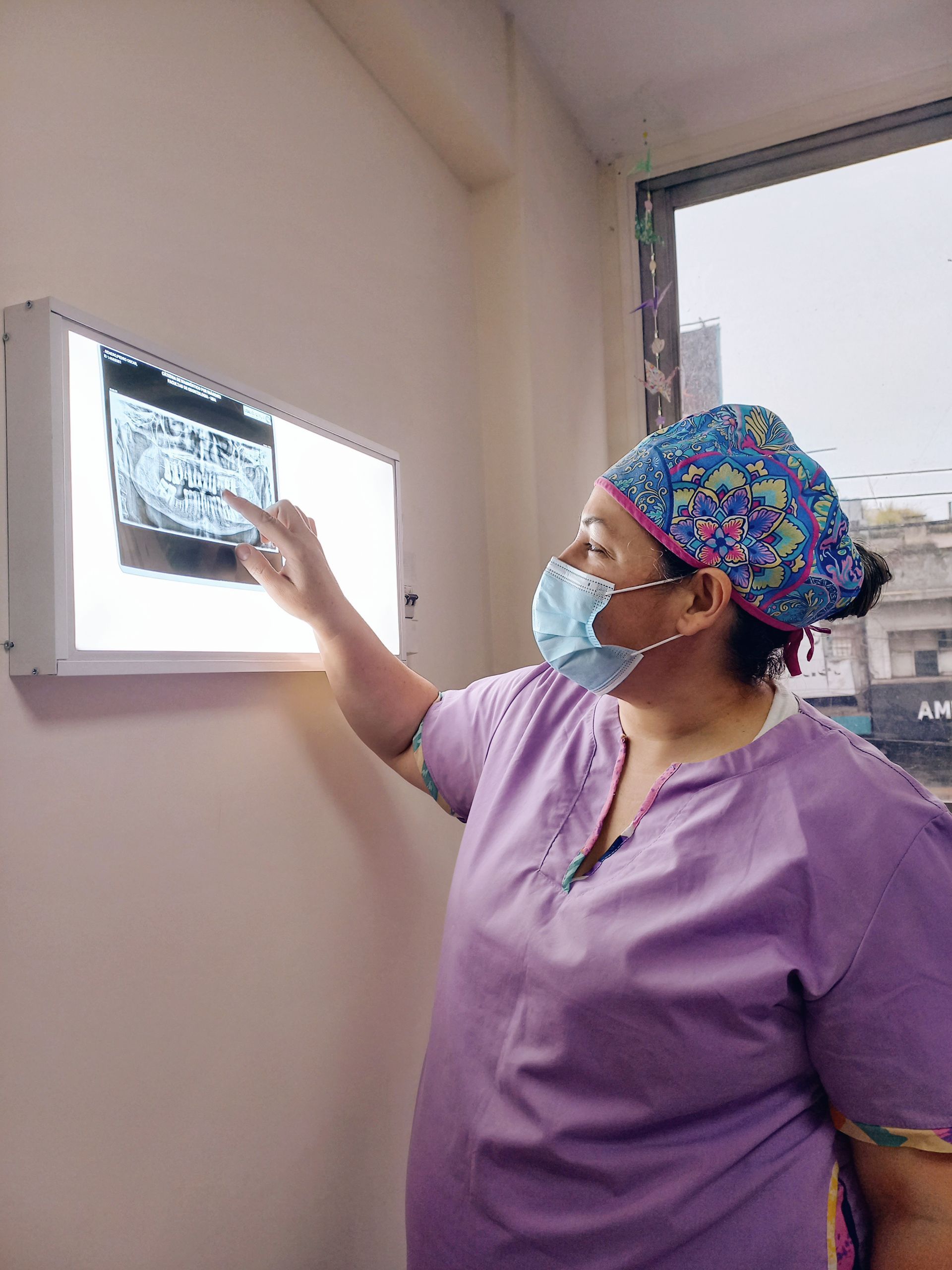 Una mujer que lleva una máscara y un sombrero está mirando una radiografía.
