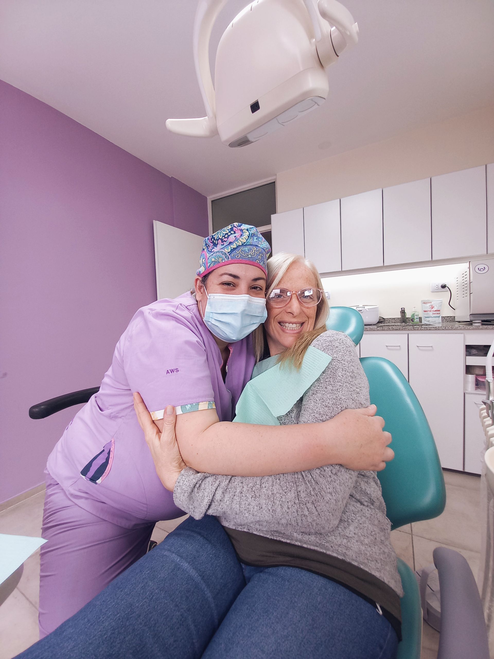 Un dentista abraza a un paciente en una silla dental.