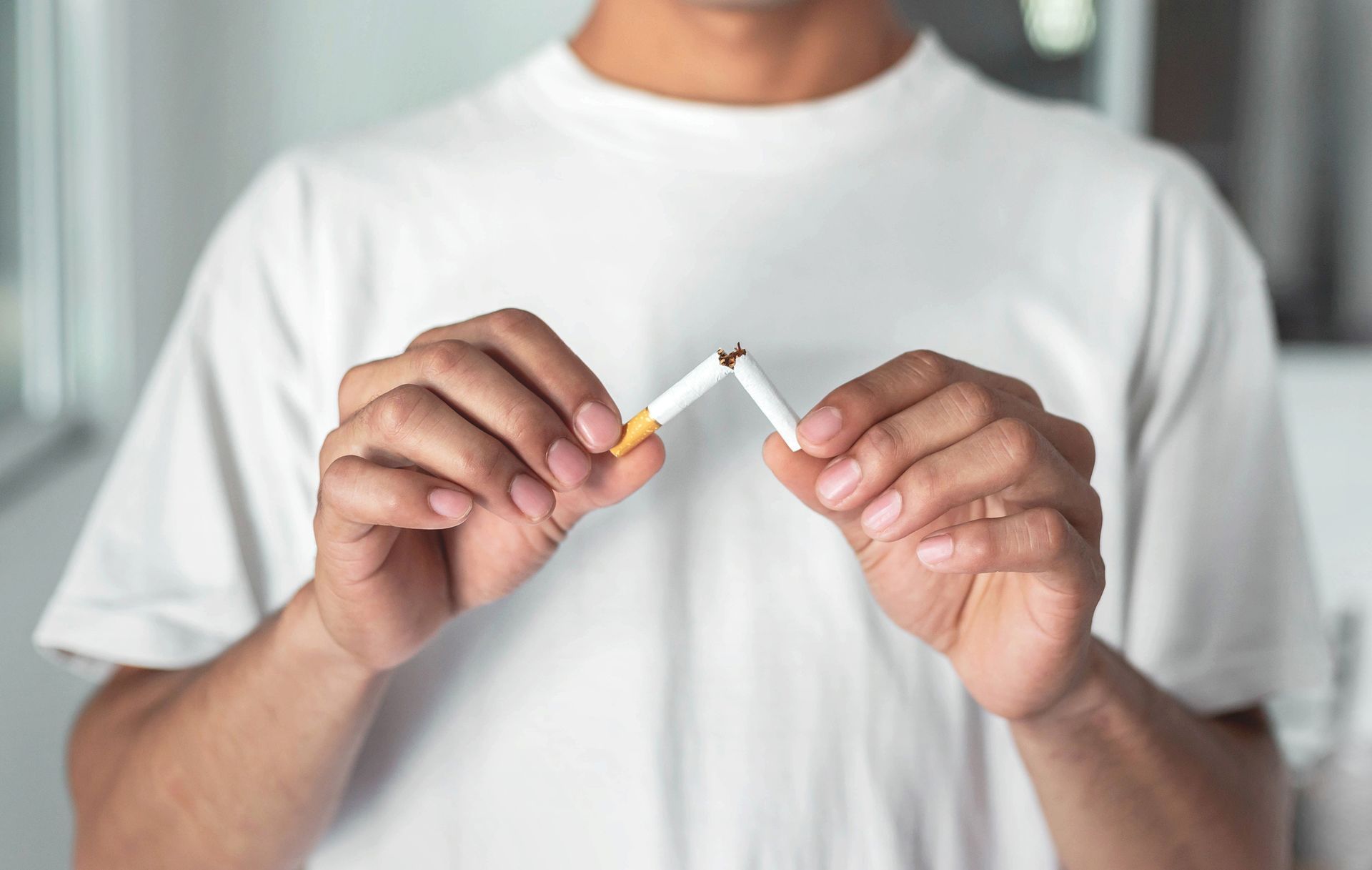 Man breaking a cigarette in half, showing quitting smoking.
