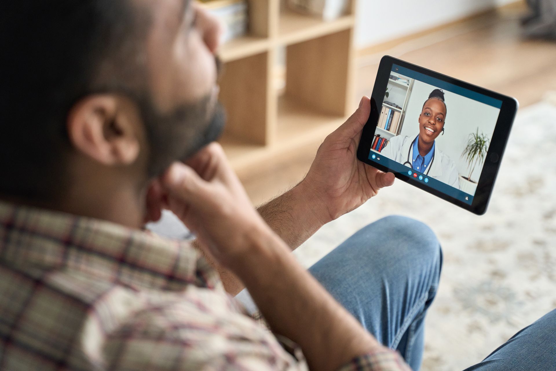 Woman in yellow shirt on video call with doctor on laptop, indoors.