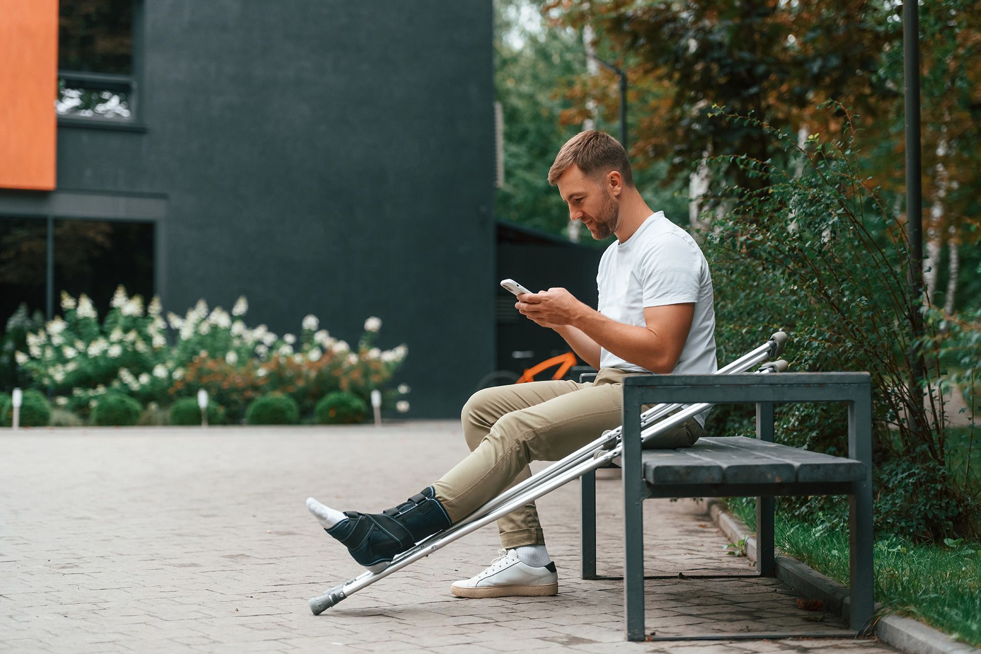 Cyclist in red shirt and blue shorts rides a black bike on a road with green trees in the background.